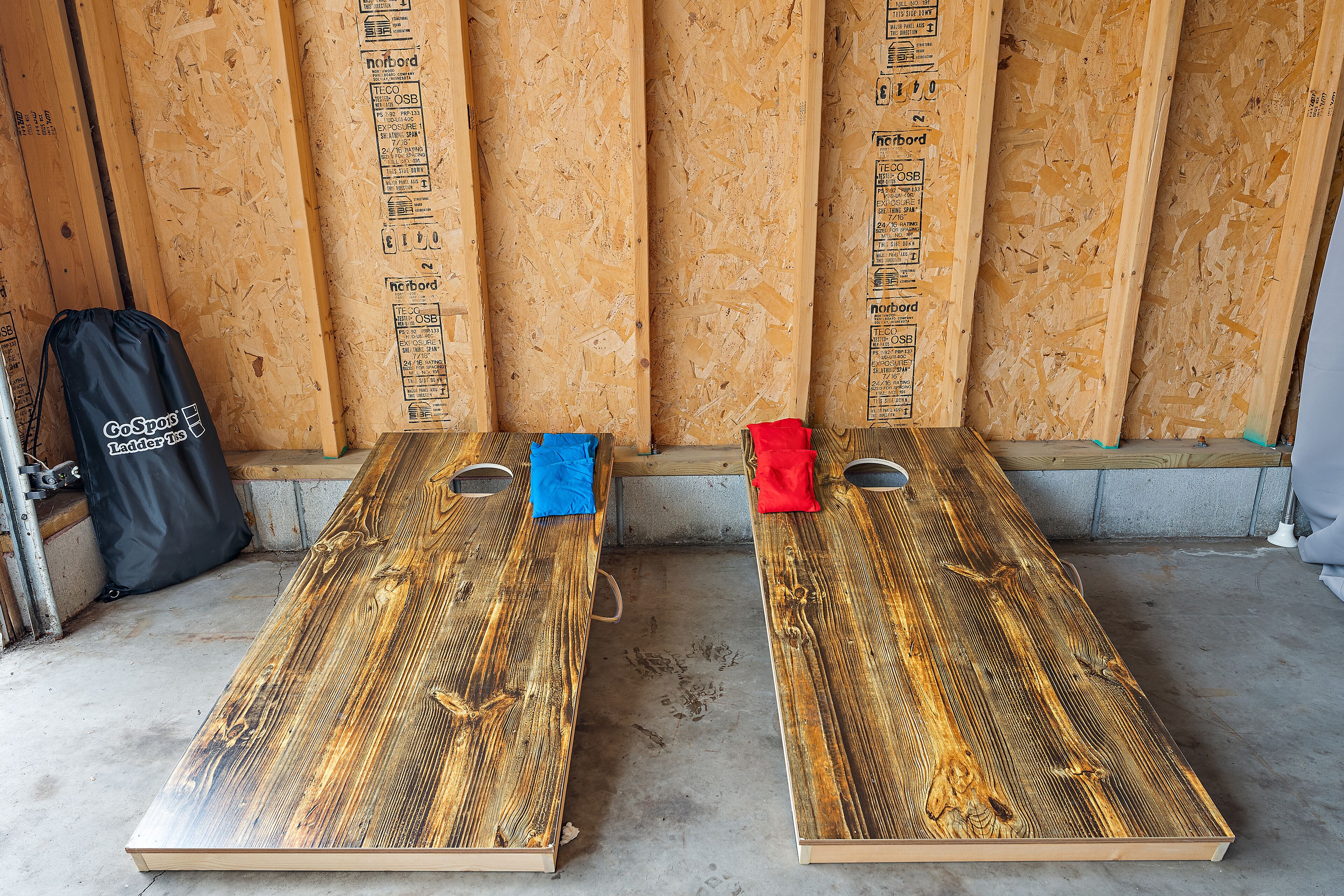 Two wooden tables with metal hoops, positioned in a room with wooden paneling and a concrete floor.