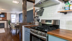 A modern kitchen with a stainless steel stove, wooden countertop, and white tiled backsplash.