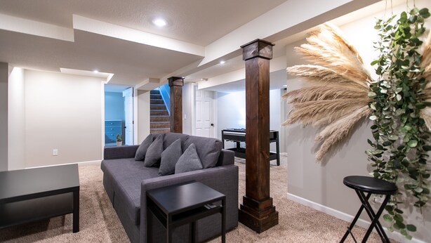 A spacious living room with a gray sofa, a coffee table, and a piano in the background.