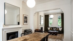Un espace repas comprenant une table et des chaises en bois, une cheminée et un coin salon avec un canapé et une table basse.