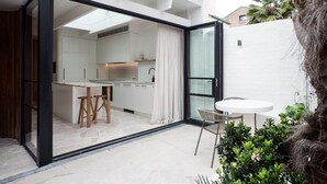 Une cuisine moderne avec des meubles blancs, un îlot central et un coin repas comprenant une table ronde et des chaises.