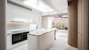 Une cuisine moderne avec des meubles blancs, un plan de travail en marbre et une vue sur la terrasse extérieure.