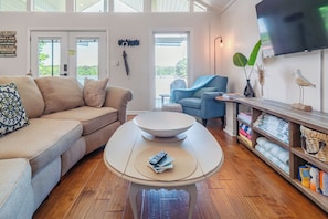 Een woonkamer met een bank, salontafel, televisie en planken met handdoeken.