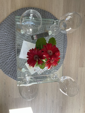 Uma mesa com tampo de vidro, quatro copos de vinho, um controle remoto e um cartão com uma mensagem.