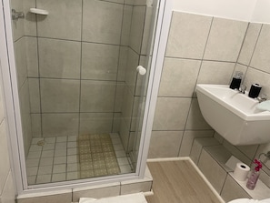 Um banheiro com chuveiro, pia e vaso sanitário.