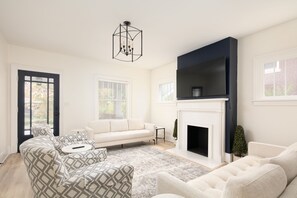 A living room with a sectional sofa, a fireplace, and a large TV. - Peaceful Chevy Chase Retreat (Lexington)