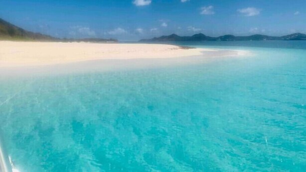 Une plage à l’eau turquoise et limpide, bordée d’un rivage sablonneux.