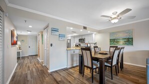 A modern kitchen with white cabinets, a microwave, and a dining area with a wooden table and chairs.