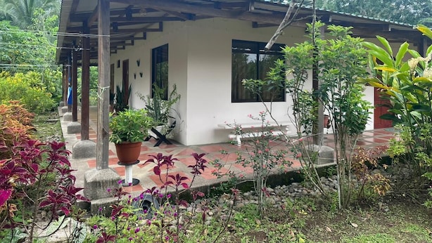 A single-story building with a tiled porch, surrounded by various plants and trees. - Riverside Lodge (Las Horquetas)