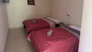 A small, clean room with two beds, a wall-mounted TV, and a power outlet. - Riverside Lodge (Las Horquetas)