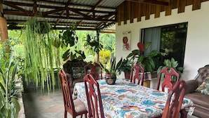 A covered patio with a dining table, chairs, and potted plants. - Riverside Lodge (Las Horquetas)