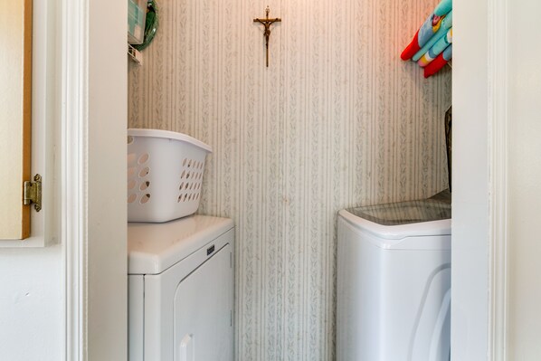 A laundry room with a washing machine, dryer, and a basket on the dryer.