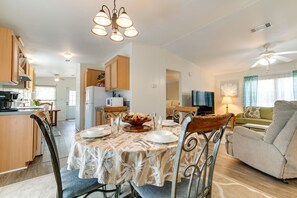 A spacious living area with a dining table set for four, a sofa, and a television.