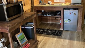 Una cocina compacta con armarios de madera, microondas, lavamanos y refrigerador.