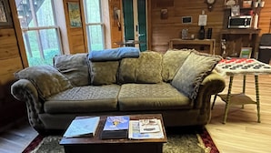 Una sala acogedora con un sofá de madera, una mesa de centro con revistas y una alfombra estampada.
