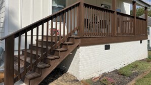 Un edificio blanco con una escalera de madera que conduce a un porche con barandilla.