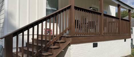 A white building with a wooden staircase leading to a porch with a railing.