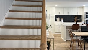 Una cocina moderna con armarios blancos, una isla central y un comedor con sillas de madera.