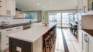 Una cocina moderna con una isla grande, taburetes de bar y vistas al exterior.