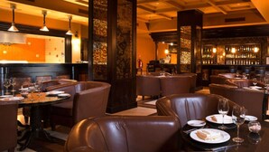 A restaurant with leather booths, tables set with plates and glasses, and a bar area with bottles. - PERFECT OASIS with private beach, golf course, kayaking, snorkeling +more (Loreto)