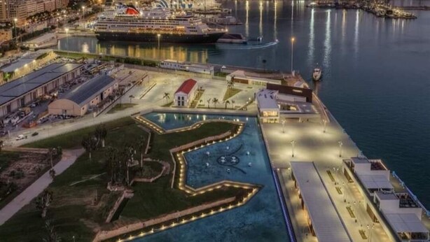 An aerial view of a waterfront area with a large pool, a marina, and a prominent mountain in the background. - 3 Bedroom Apartment in Palermo (Palermo)