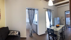 A living room with a sofa and a dining area with a table set for two. - 3 Bedroom Apartment in Palermo (Palermo)