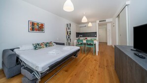 Una habitación pequeña con cama, kitchenette y televisión.