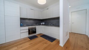 Una cocina moderna con armarios blancos, horno integrado y un salpicadero de encimera negro.