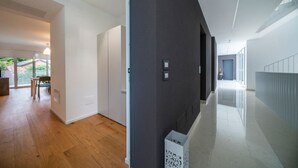 Un interior moderno con piso de madera, una pared de acento oscura y un pasillo que conduce a una puerta.