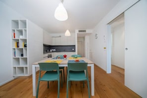 Une cuisine moderne avec des meubles blancs, une table à manger en bois et des chaises de couleur turquoise.