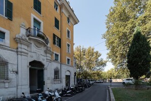 Une rue bordée de motos garées et un bâtiment au style architectural classique.