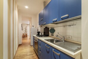 Une cuisine moderne avec des armoires bleues, un évier en acier inoxydable et un plancher en bois.