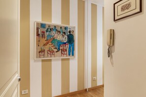 Un mur à rayures orné d’un tableau encadré représentant une scène de groupe et d’un téléphone fixé au mur.