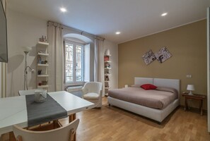 Ein Schlafzimmer mit Bett, Stuhl, Tisch und Fenster.