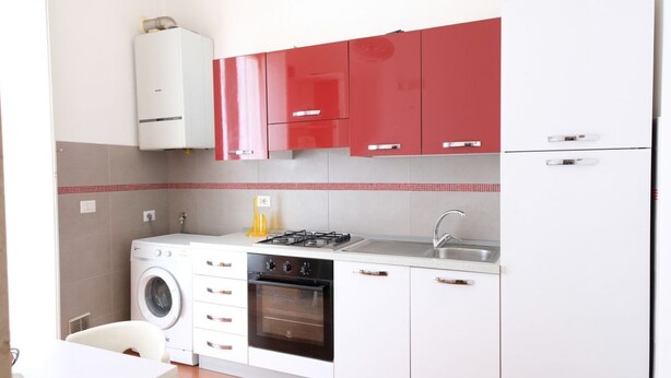 Een kleine keuken met een wasmachine, oven en een gasfornuis.