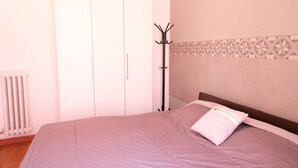 Een slaapkamer met een bed, kapstok, kledingkast en radiator.