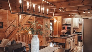 A wooden cabin interior with a dining area, kitchen, and staircase. - The Burrow Lodge! Pet Friendly! Hot Tub! Sleeps 16 (Logan)