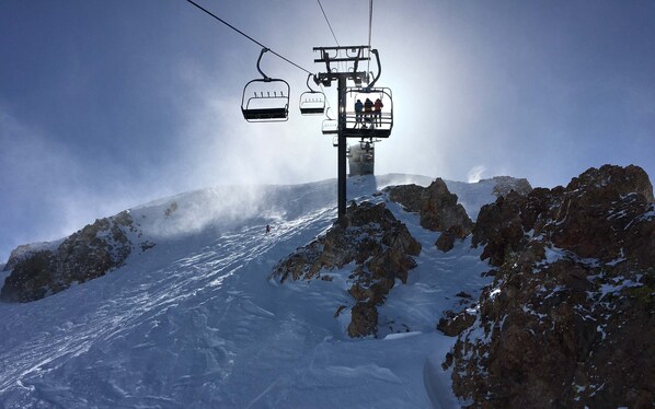 A ski lift with chairs moving up a snowy mountain slope.