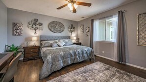 A bedroom with a bed, nightstands, a desk, a ceiling fan, and wall art. - Brand New! Restoration Retreat (Flagstaff)