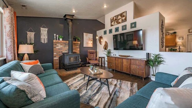 A living room with a sofa, a coffee table, a fireplace, and a TV mounted on the wall. - Brand New! Restoration Retreat (Flagstaff)
