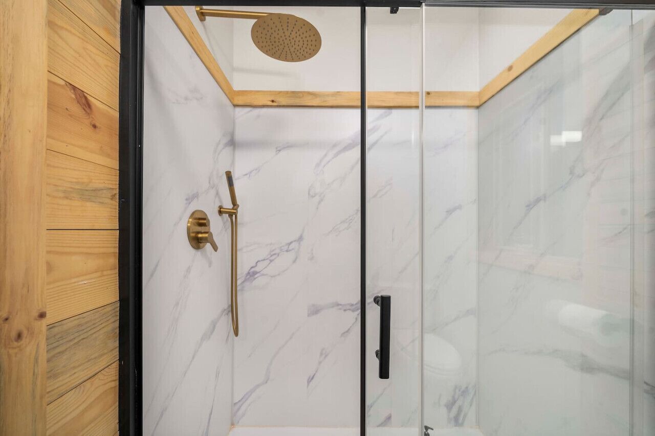 Ducha con cerramiento de vidrio, techo de madera y paredes de mármol.