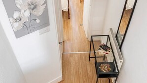 Un escalier dont les marches sont recouvertes de moquette mène à une pièce dotée d’un plancher en bois, d’une table en métal noir sur laquelle sont posés des livres, et d’une œuvre d’art encadrée accrochée au mur.