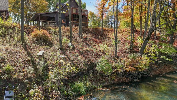 Eine Hütte mit einer Terrasse und einem Fluss im Vordergrund.