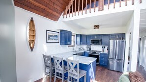 Eine moderne Küche mit blauen Schränken, einem Edelstahlkühlschrank und einer Holzbalkendecke.