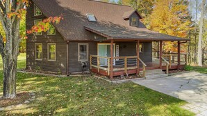 Eine rustikale Holzhütte mit Veranda und kleiner Terrasse, bewölkter Himmel.