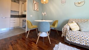 A modern living space with a dining area, a sofa, and a kitchen in the background. - GIALLOMANGO Apt in Lucca (Lucca)