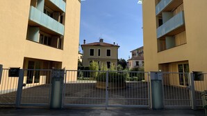 A gated entrance to a residential building complex with beige exterior walls and blue balconies. - GIALLOMANGO Apt in Lucca (Lucca)
