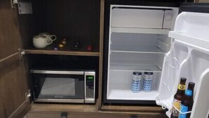 A compact kitchenette with a microwave, a small refrigerator, and a drawer unit. - Luxury Suite Downtown Berlin 302 (Millersburg)