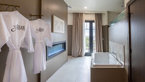 Une salle de bain moderne avec une baignoire, un porte-serviettes avec des peignoirs, et une grande fenêtre avec des rideaux.
