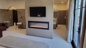 Ein modernes Wohnzimmer mit Flachbildfernseher, integriertem Kamin, rundem Tisch und einer Sitzecke.